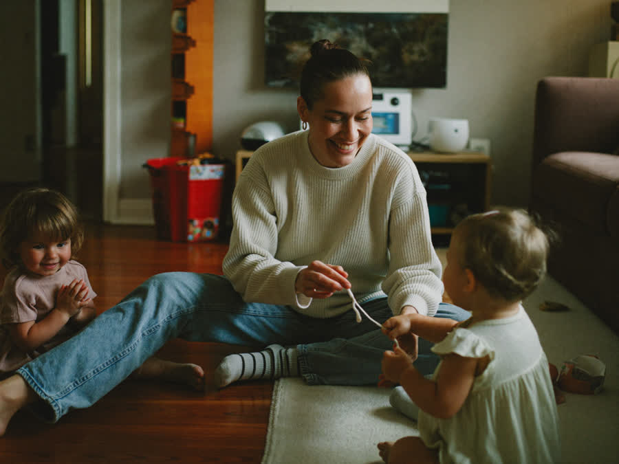A relaxed mom playing on the floor with her two young kids